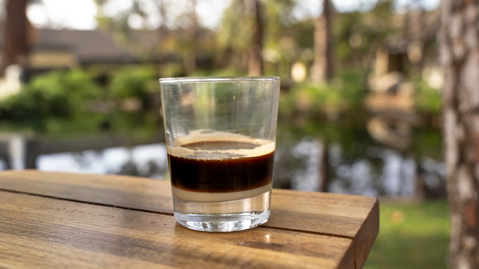 A layered espresso shot resting on a courtyard table